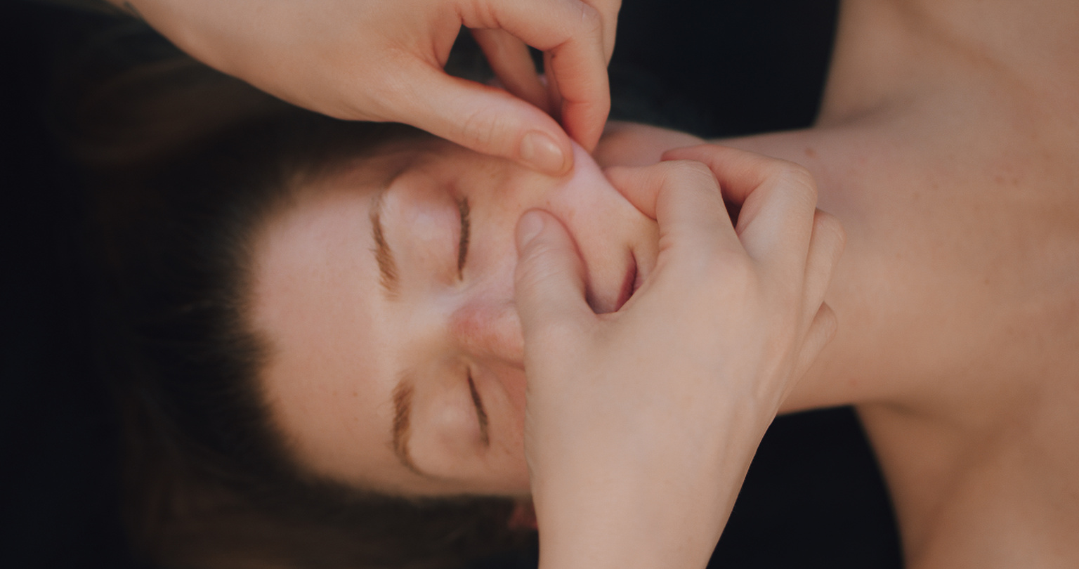 Kobido facial massage. The beautician massages the client's cheeks.