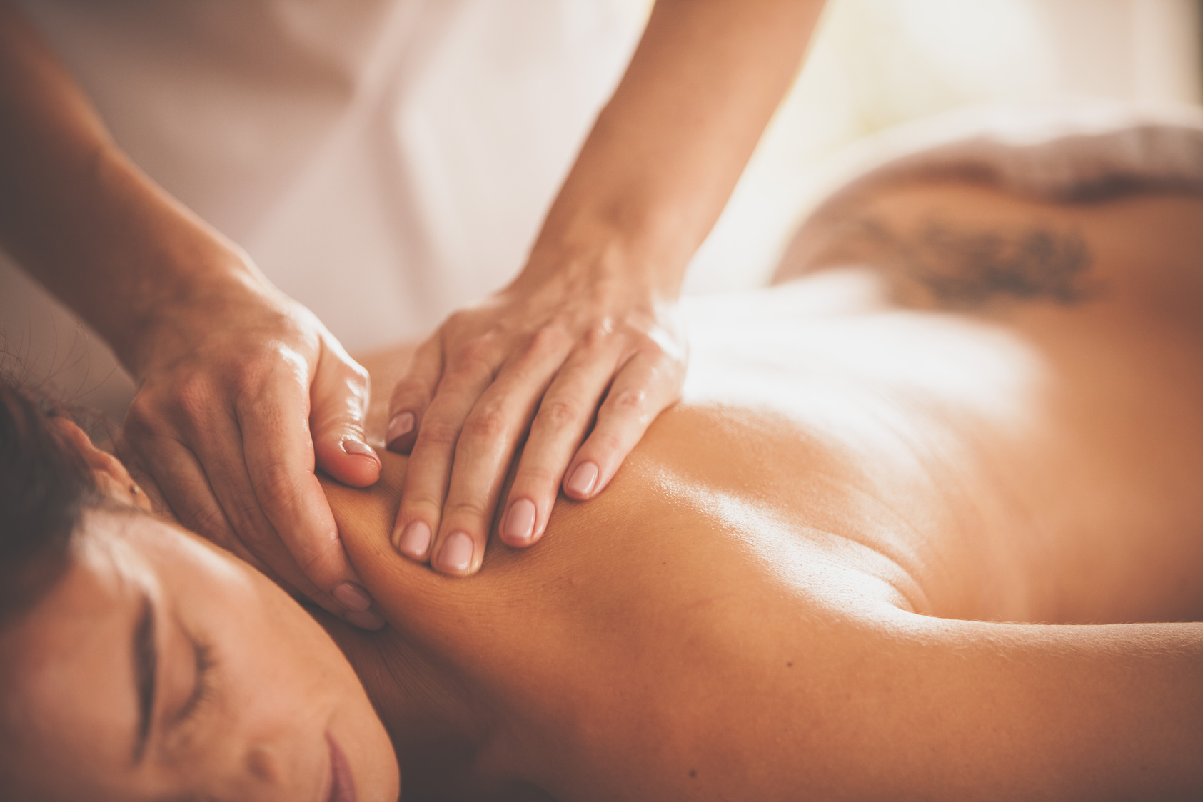 Massage therapist massaging woman's shoulders